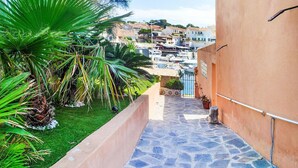 A narrow stone pathway leading to a building with a view of a marina and houses in the background.