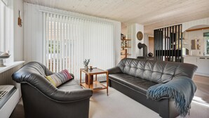 A living room with a sofa, a coffee table, and a radiator. There is a window with blinds and a view of the outdoors. - Lovely home in Hemmet with WiFi (Hemmet)