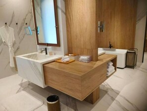 Bathroom features a sink, mirror, and towels, with a wooden column and trash can.