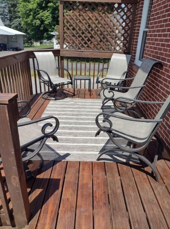 Relax in comfort on this outdoor patio with a wooden deck, featuring four chairs and a small table.