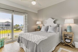 Quarto com uma cama grande, duas mesas de cabeceira com luminárias, vista para o exterior e uma varanda.