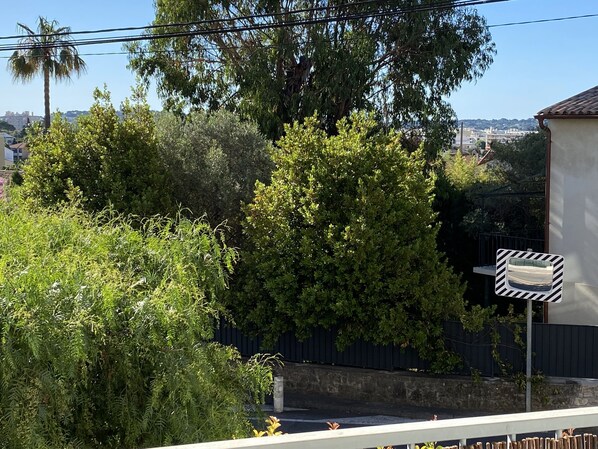 Zona residencial con abundante vegetación, cielo despejado y un horizonte urbano a lo lejos.