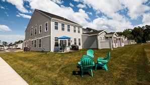 Une maison à deux étages avec un patio couvert, une pelouse et une clôture.