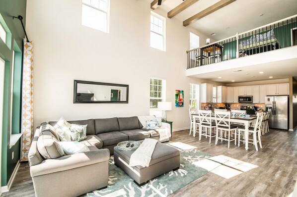 A spacious living area with a sectional sofa, a dining table with chairs, and a kitchen with modern appliances.