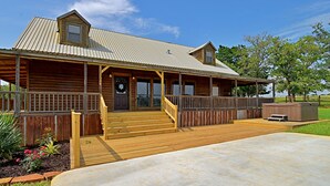 A wooden lodge with a porch, a hot tub, and a covered deck area. - 4D Guest Ranch~Large private pool with volley ball and basket ball nets (Waelder)