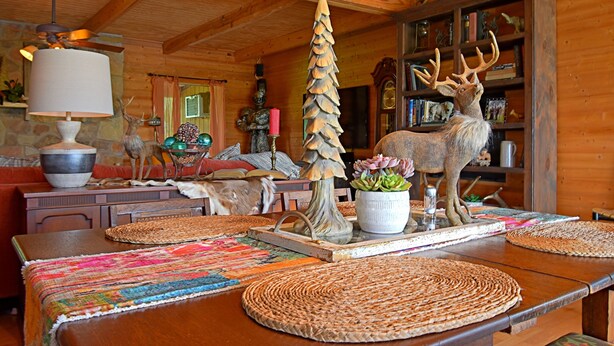 A wooden interior with a dining table, woven placemats, a chandelier, and a deer sculpture. - 4D Guest Ranch~Large private pool with volley ball and basket ball nets (Waelder)