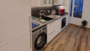 Een moderne keuken met witte kastjes, een ingebouwde wasmachine en een raam met uitzicht.