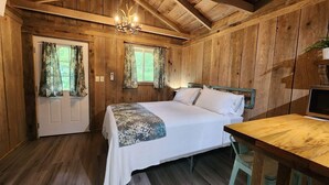 Una habitación de cabaña de madera con una cama, un escritorio y una araña.