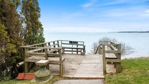 A wooden pier leading to a calm body of water, surrounded by trees and a clear sky. - Luxe Lodges on Lake Erie ~ Bunkie ~ Beach Access (Port Dover)