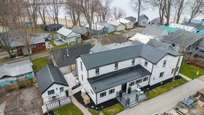 A large, two-story house with a flat roof, a front porch, and a garage. - Luxe Lodges on Lake Erie ~ Bunkie ~ Beach Access (Port Dover)
