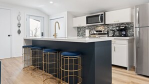 A modern kitchen with a central island, bar stools, stainless steel appliances, and a view of the outdoors.