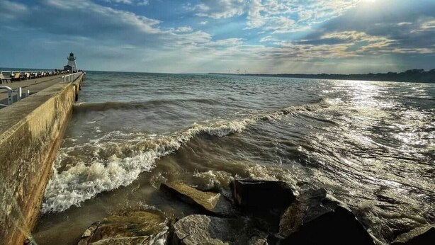 A pier extending into the sea with waves crashing against it.