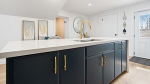 A modern kitchen with a white countertop, dark cabinets, and gold handles.