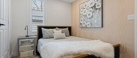 Ein Schlafzimmer mit Bett, Nachttisch und Fenster.