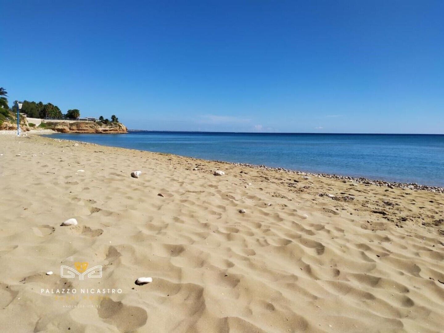 Una playa arenosa con huellas y un cielo azul despejado.