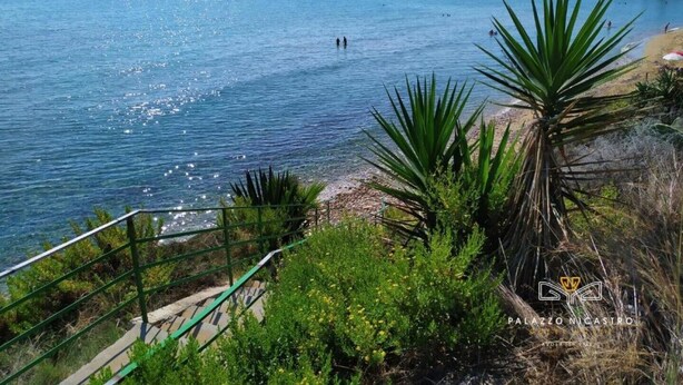 A coastal view with a clear sky, a sandy beach, and a rocky outcrop in the distance. - PALAZZO NICASTRO gh - Red House apartment (Avola)