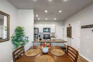 A modern kitchen with white cabinets, a central island, and a dining area with a wooden table and chairs. - Spacious 2-Story, Pet&Fam Friendly, WFH, Gym&Pool (Draper)