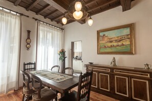 A dining area with a wooden table, chairs, a chandelier, a painting, and a cabinet. - Old Bridge Boutique (Firenze)