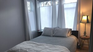 A bedroom with a bed, a nightstand, a lamp, and a window with curtains. - Beautiful newly updated home in Boulder! Entrance on side of house up stairs. (Boulder)