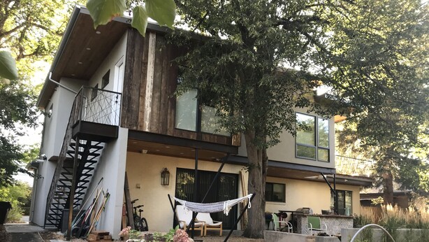 A modern two-story house with a balcony, a hammock, and a garden area with steps leading up to the entrance. - Beautiful newly updated home in Boulder! Entrance on side of house up stairs. (Boulder)