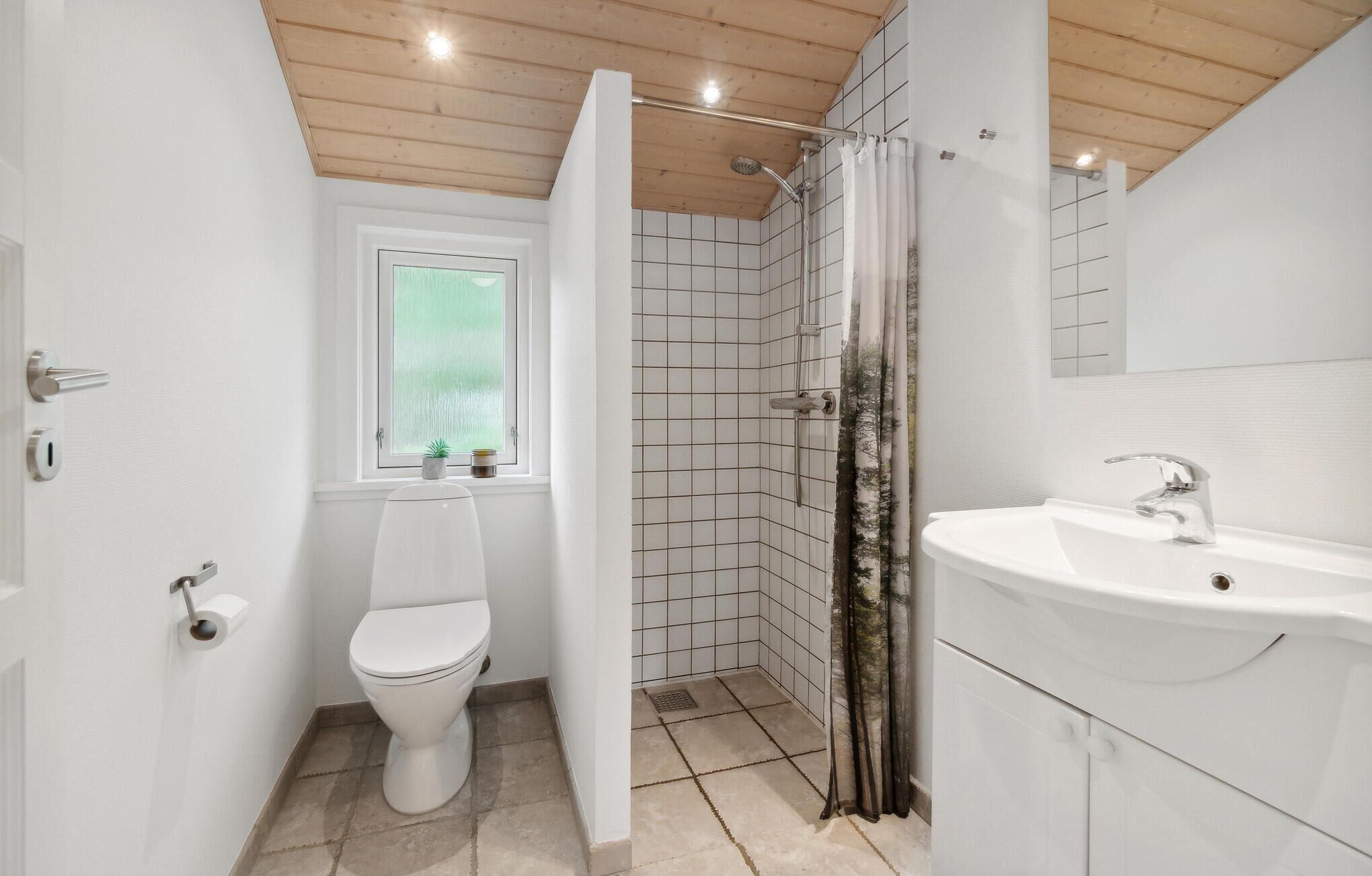 A bathroom with a toilet, shower, and sink.