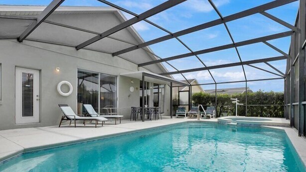 A swimming pool with lounge chairs and a covered patio area. - South Facing Pool & Spa- 2 Master Bedrooms (Clermont)
