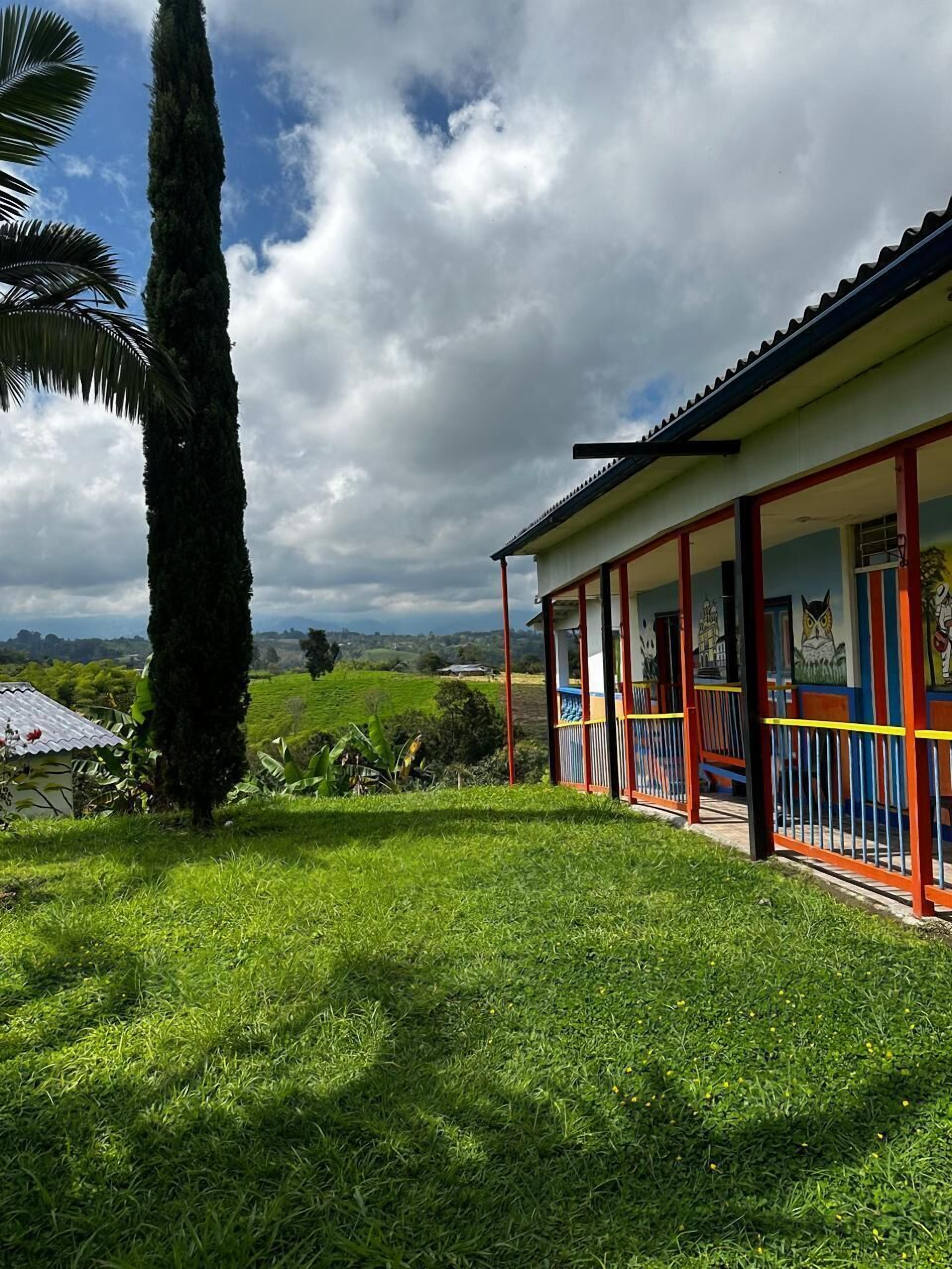 A building with a red and white exterior, a covered porch, and a view of a green landscape.