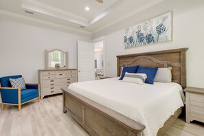 Un dormitorio con una cama grande, un aparador, una silla y un cuadro en la pared.