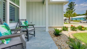 A covered porch with outdoor seating, a small garden, and a view of the street. - Bright Foley Home w/ Patio - 7 Mi to Wharf & Beach (Foley)