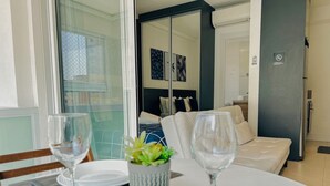 Ett hotellrum med en matplats, en säng med ett blått sänggavel, en liten krukväxt och utsikt över omgivningen.