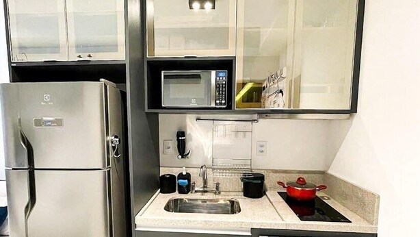 Eine kleine Küche mit Kühlschrank, Mikrowelle, Spüle und Backofen.