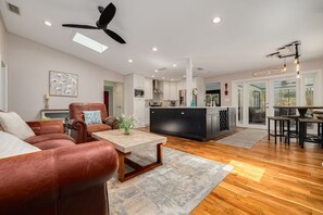 A spacious living room with a leather sofa, a coffee table, and a ceiling fan.
