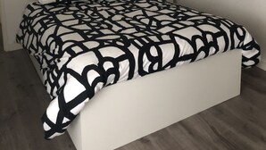 Una camera da letto con un letto, due quadri appesi al muro, un comodino con una lampada e un pavimento in legno.