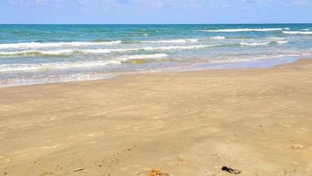 A beach with clear skies and calm waves.