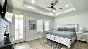 A bedroom with a bed, bedside tables, a ceiling fan, and a window with blinds.
