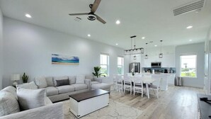 A spacious living room with a grey sofa set, a coffee table, and a ceiling fan.