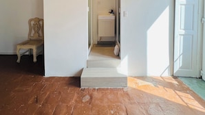 Une pièce avec un plancher en bois, une porte blanche, une chaise et un téléviseur fixé au mur.