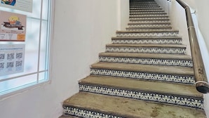 Un escalier orné de carreaux noirs et blancs, un plafond en bois et une fenêtre affichant des informations de sécurité pour les voyageurs.