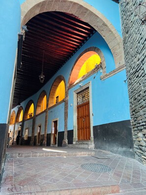 An arched corridor with a tiled floor, a wooden door, and a stone wall.