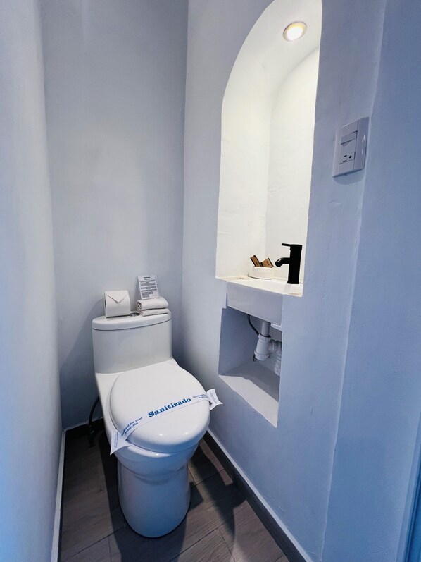 A small, modern bathroom with a white toilet, a mirror above the sink, and a towel rack.