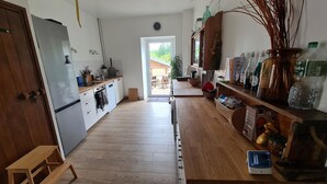 Une cuisine dotée d’un plancher en bois, de meubles blancs, d’un réfrigérateur en acier inoxydable et de divers appareils de cuisine.