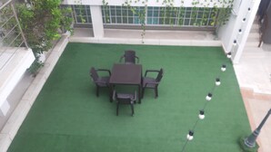 A patio area with a table and chairs, surrounded by a green lawn. - Habitacion Extragrande Cerca al Parque Venezuela (Barranquilla)