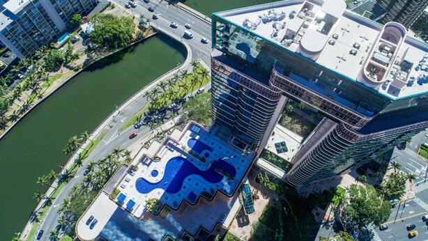 A high-rise building with a rooftop pool and a curved swimming pool below. - Stunning High-Floor Unit with Spectacular Ocean, Diamond Head, and Waikiki Views (Honolulu)