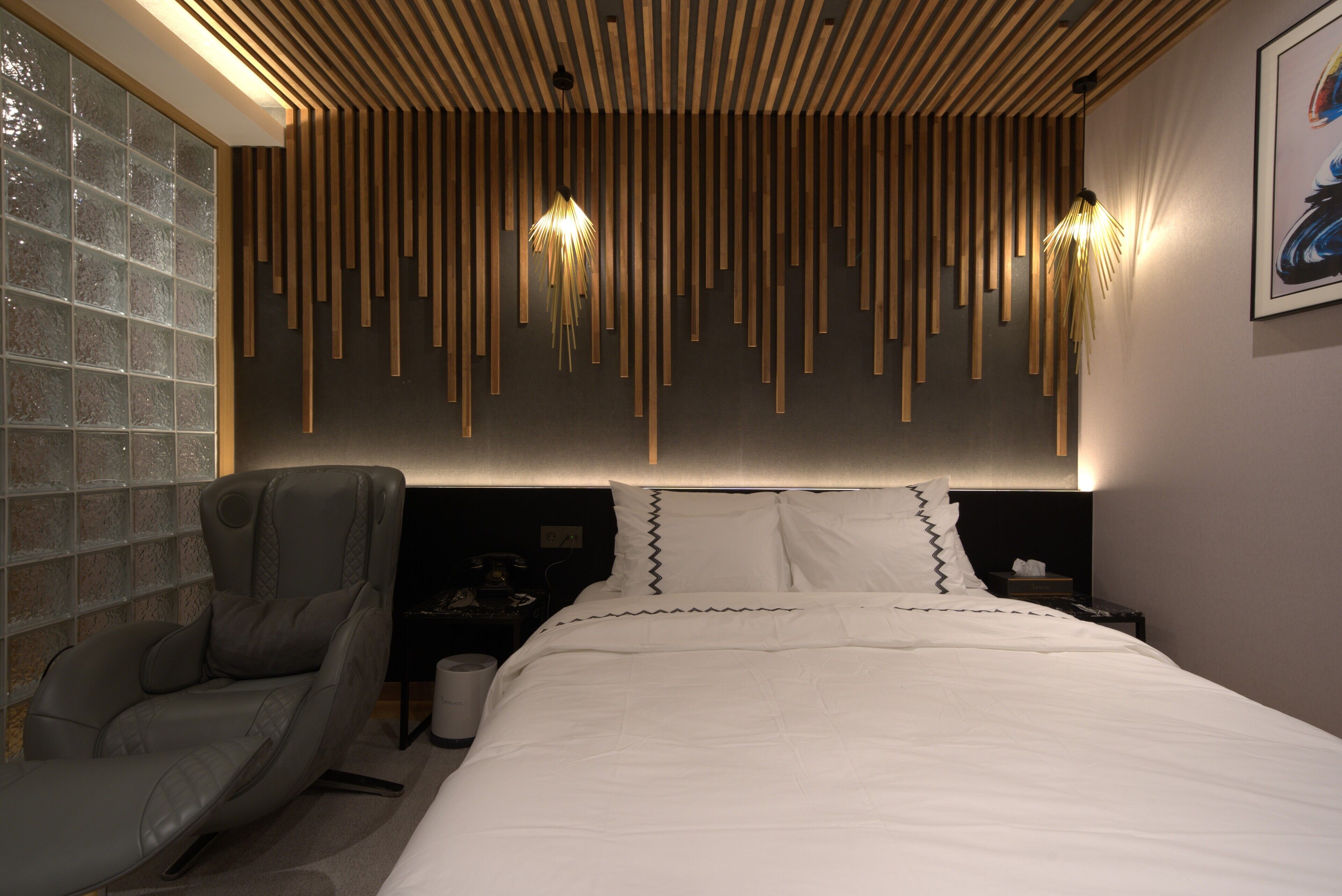 Un dormitorio moderno con una cama grande, una silla de masajes y un diseño único de techo de listones de madera.