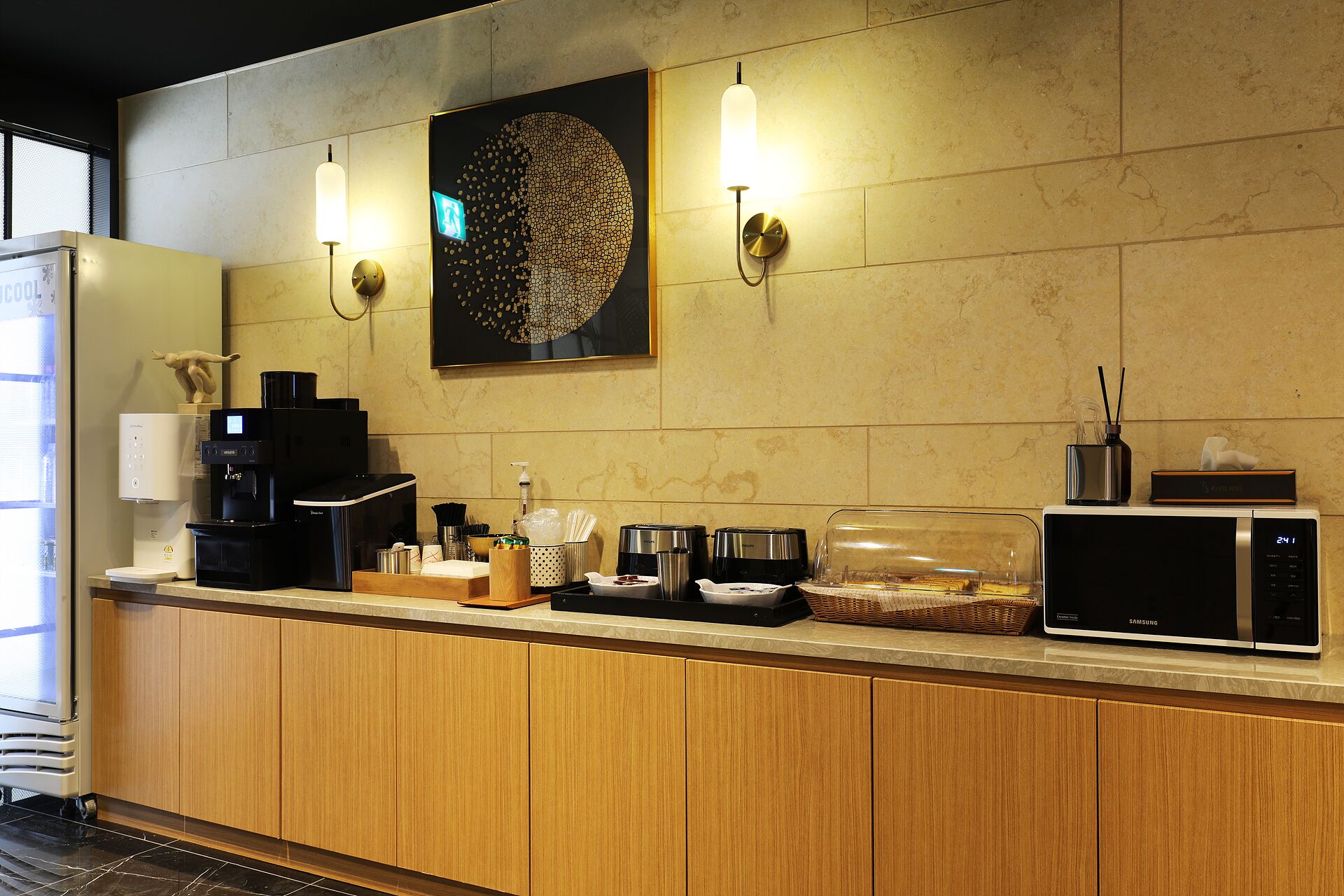 A modern kitchen with a coffee machine, microwave, and a decorative wall piece.