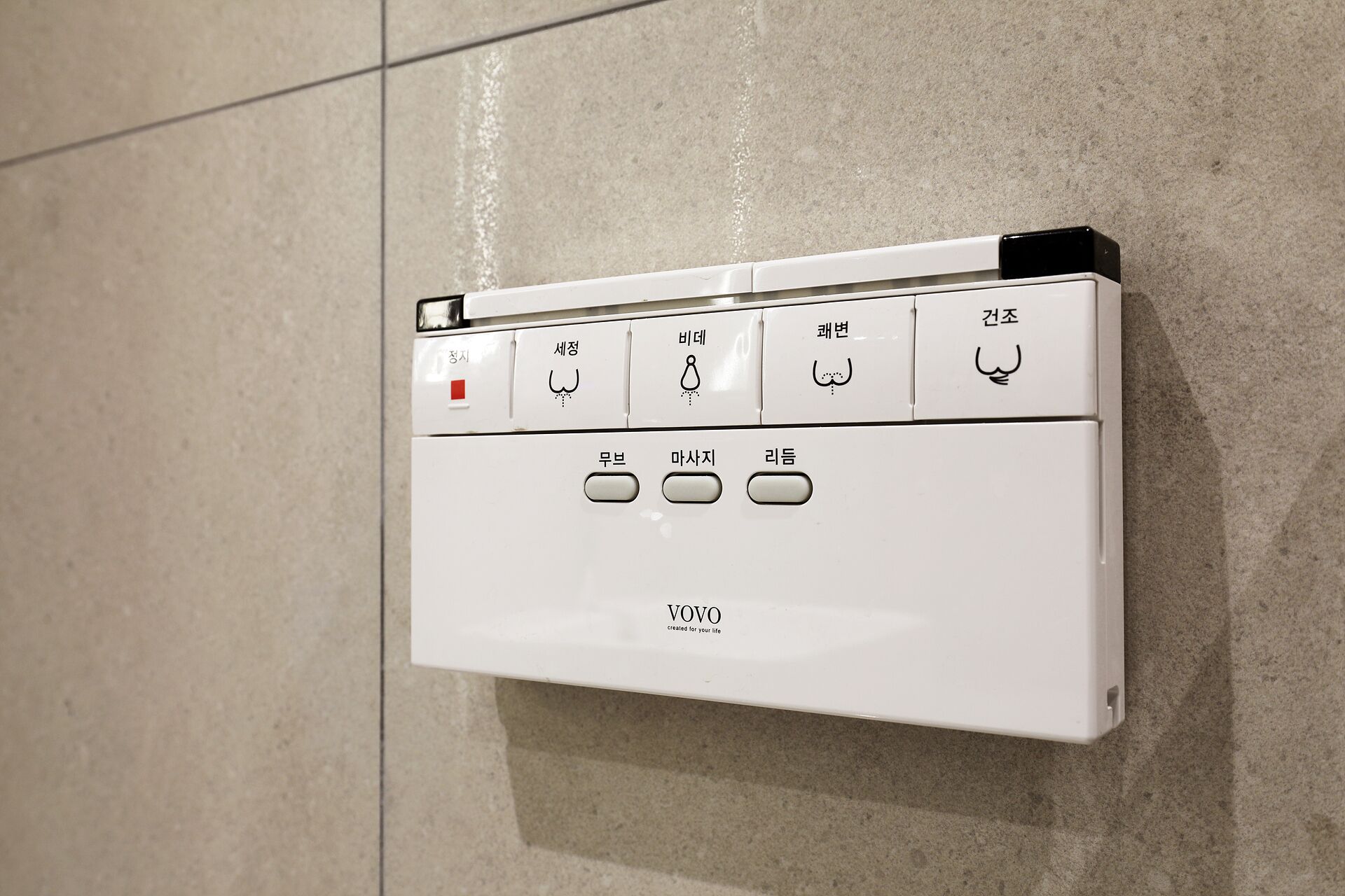 Et panel monteret på væggen med flere knapper og mærkenavnet 'VOVO'.