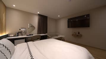 Una habitación de hotel moderna con una cama grande, un escritorio con espejo, un televisor de pantalla plana y una mesita.