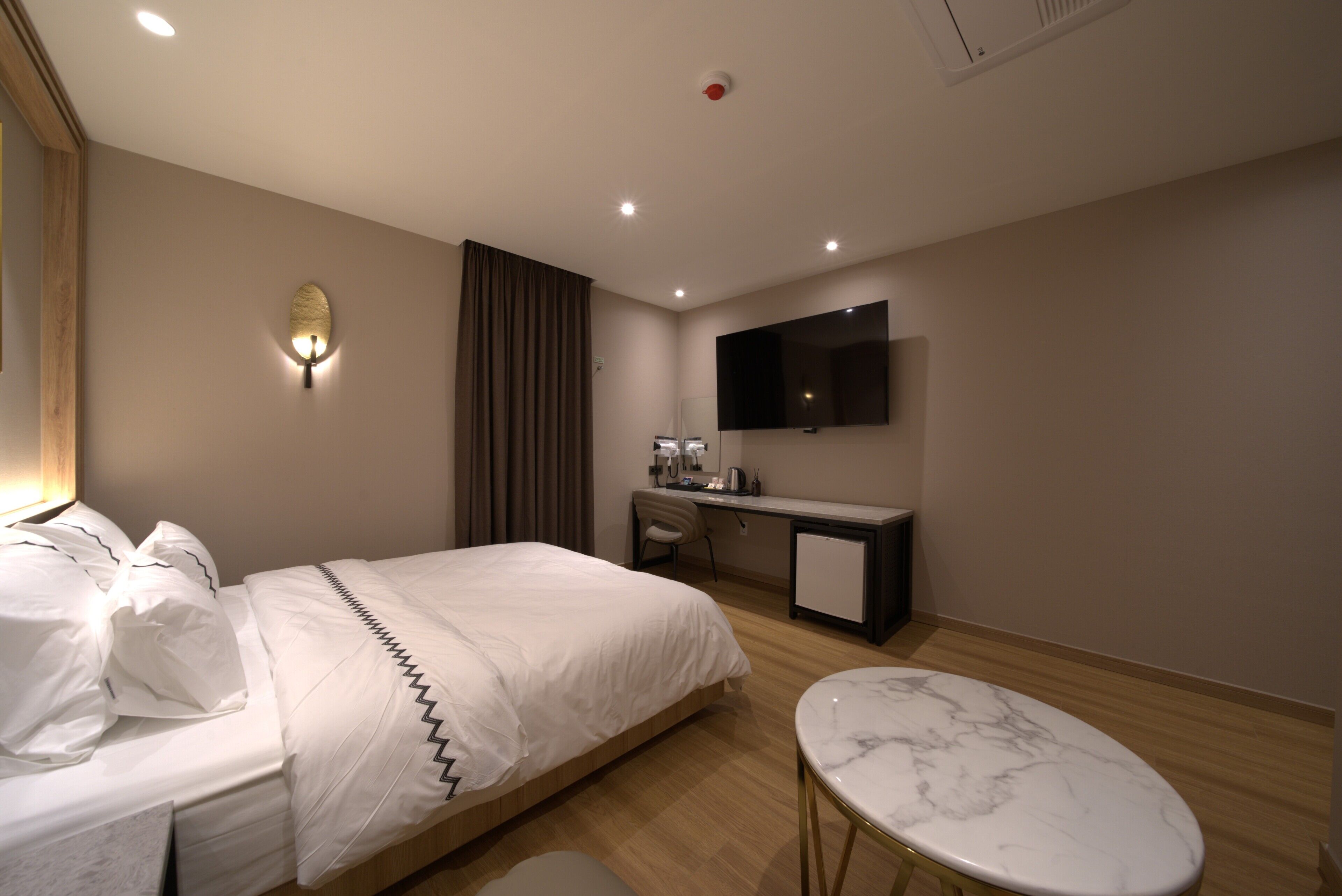 Una habitación de hotel con cama, escritorio, televisión y una mesita.