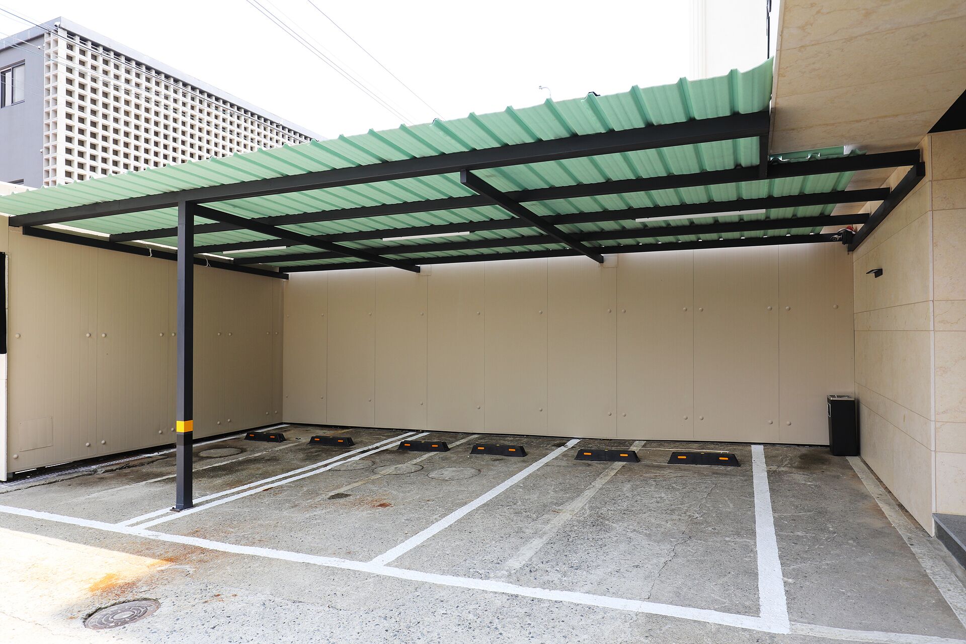 Un parking souterrain doté de nombreuses places de stationnement, d’un toit en métal vert et de murs de couleur beige.
