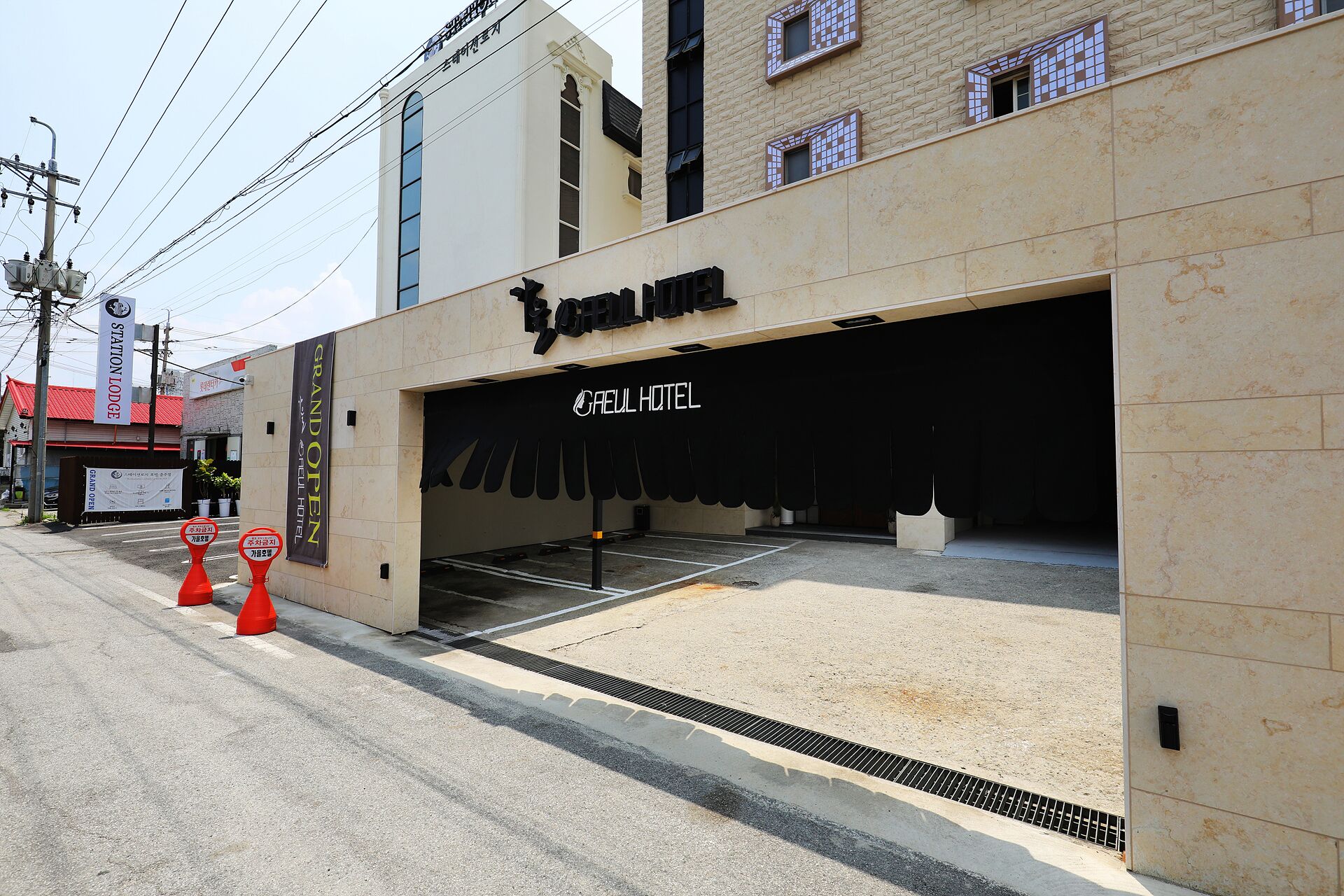 A hotel entrance with a black awning and a sign reading "Grand Open Hotel".